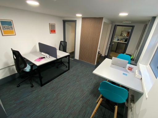 4 hot desks available for rent, 2 on large desk separated by privacy screen.