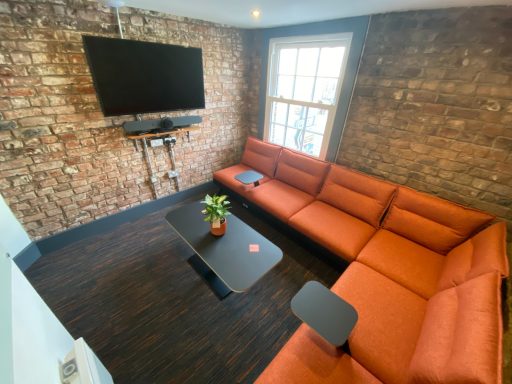 Small meeting room with orange sofa L shaped seating.